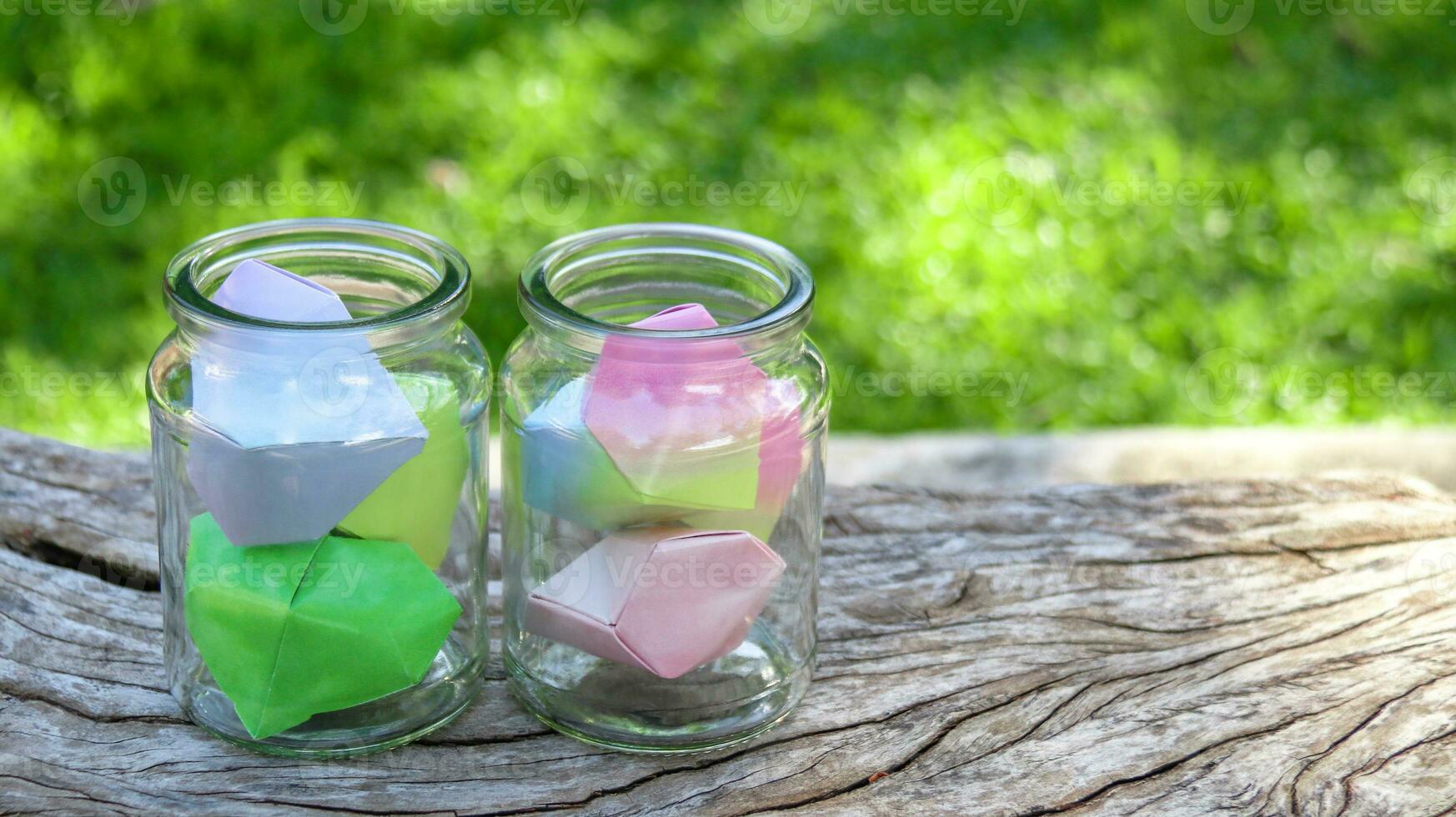 Paper hearts in glass bottles on wooden floor with blurred trees background concept for cheering LGBTQ people around the world photo