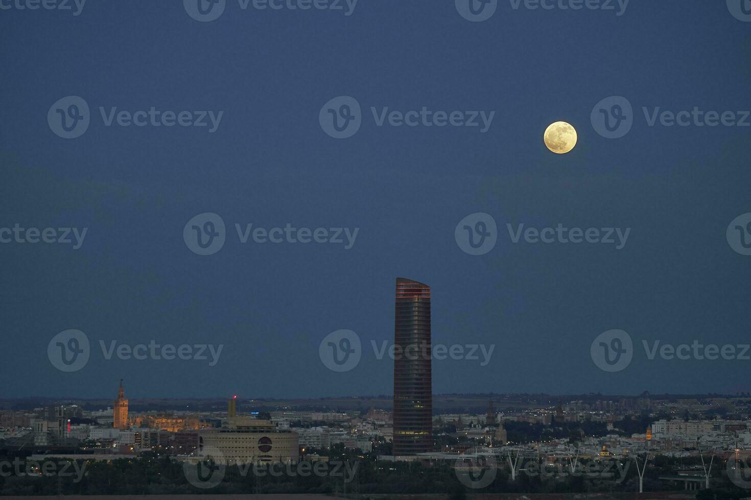 The moon illuminates the sky of seville, skyline of seville, Giralda and Pelli Tower photo