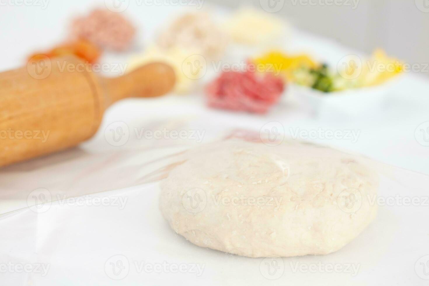 Pizza dough ball ready to stretch and pizza ingredients. Pizza preparation. photo