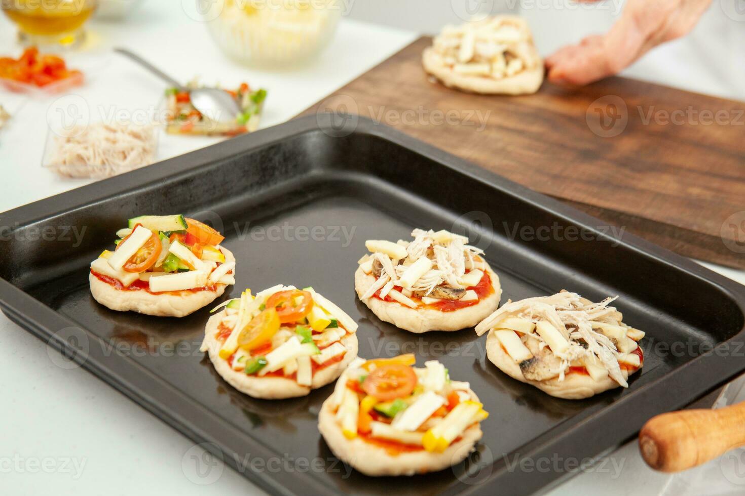 Ready to be baked mini pizzas. Delicious home made mini pizzas preparation. photo