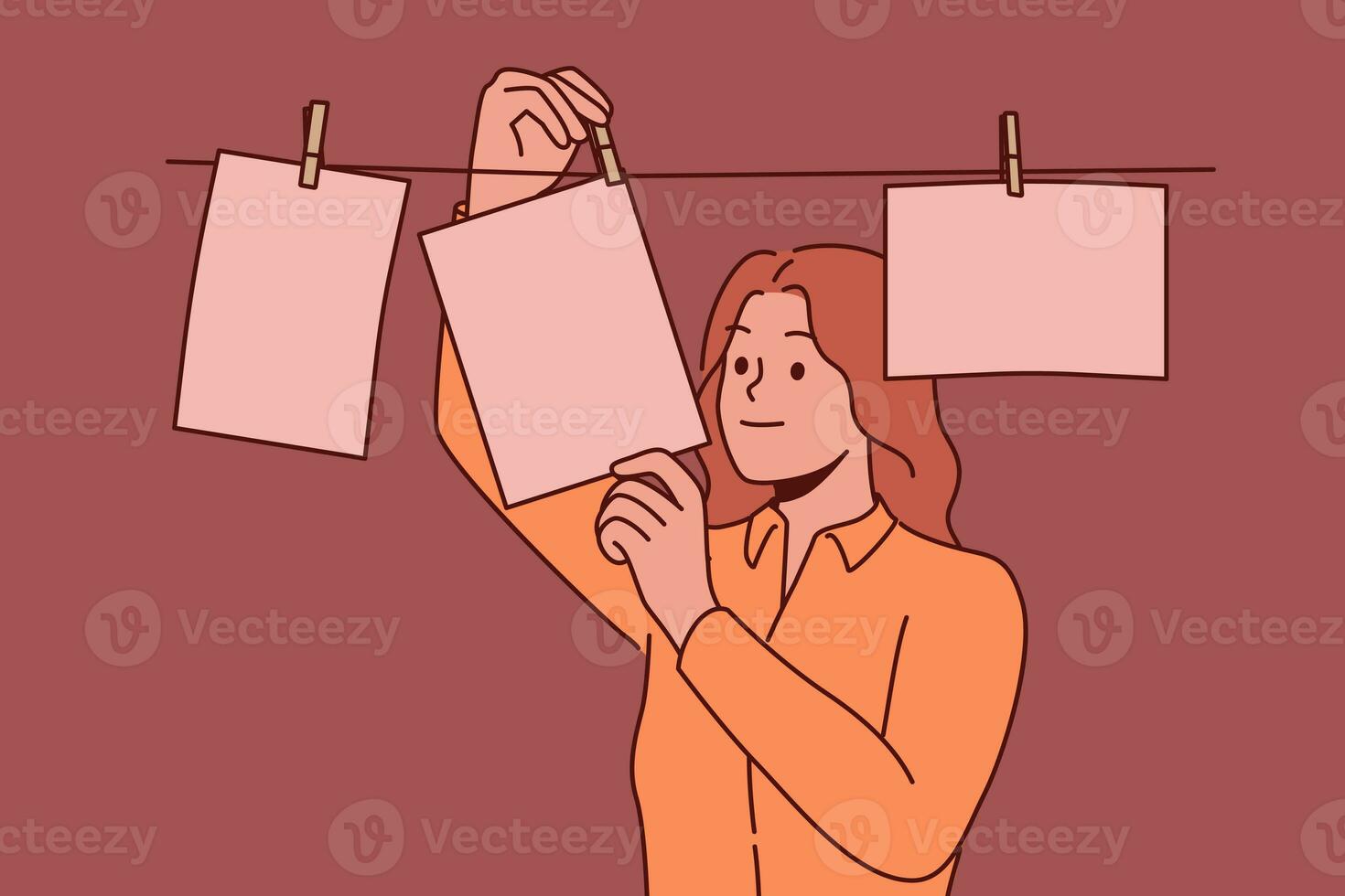 Woman photographer stands using retro technology and looks at pictures hanging on rope photo
