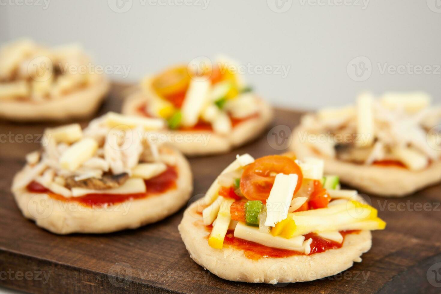 Ready to be baked mini pizzas. Delicious home made mini pizzas preparation. photo