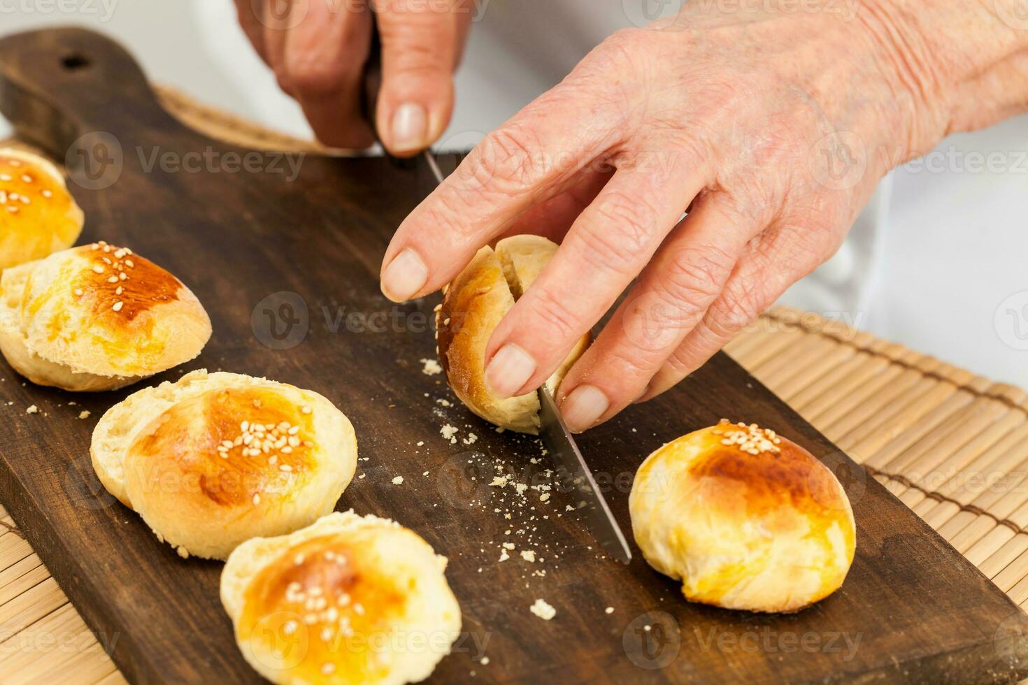 Cutting small bread buns for mini burgers. Step by step preparation of mini burgers. Homemade mini burgers for children or appetizers. Small hamburgers. photo