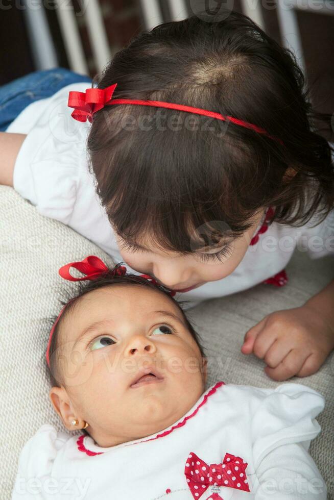 One month old baby girl at home with her big sister. Love between siblings concept. Family concept. photo