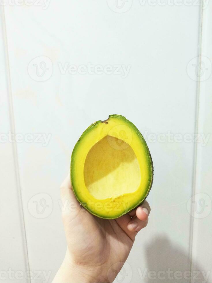 woman holding a slice of fresh ripe avocado photo