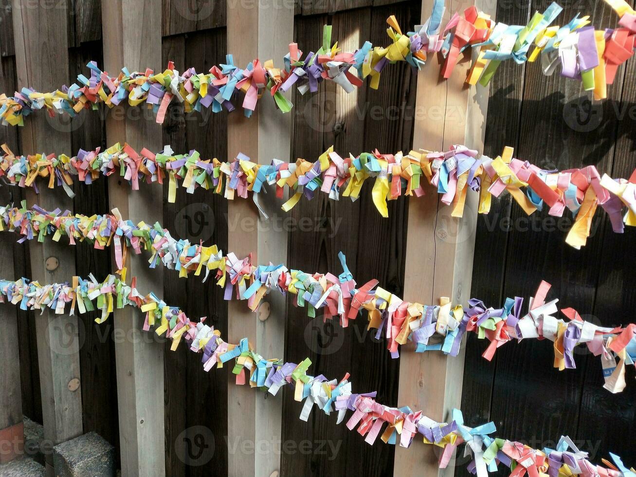 Colorful prayer flags attached to a wooden fence at a Buddhist temple photo