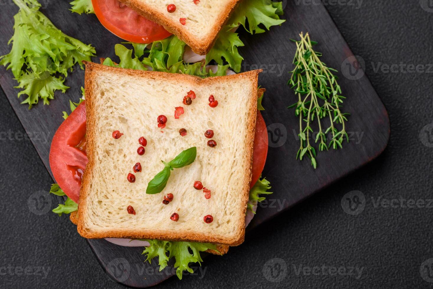 delicioso emparedado con tostada, jamón, Tomates, queso y lechuga foto