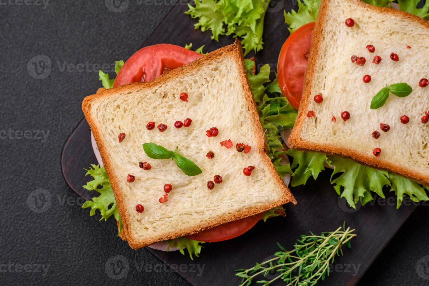 delicioso emparedado con tostada, jamón, Tomates, queso y lechuga foto