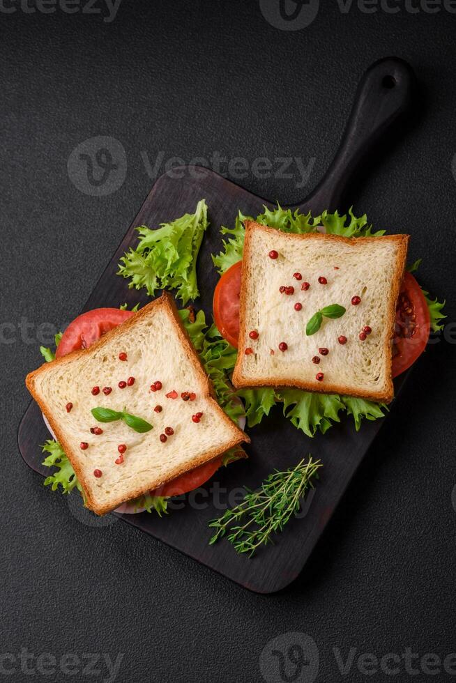 delicioso emparedado con tostada, jamón, Tomates, queso y lechuga foto