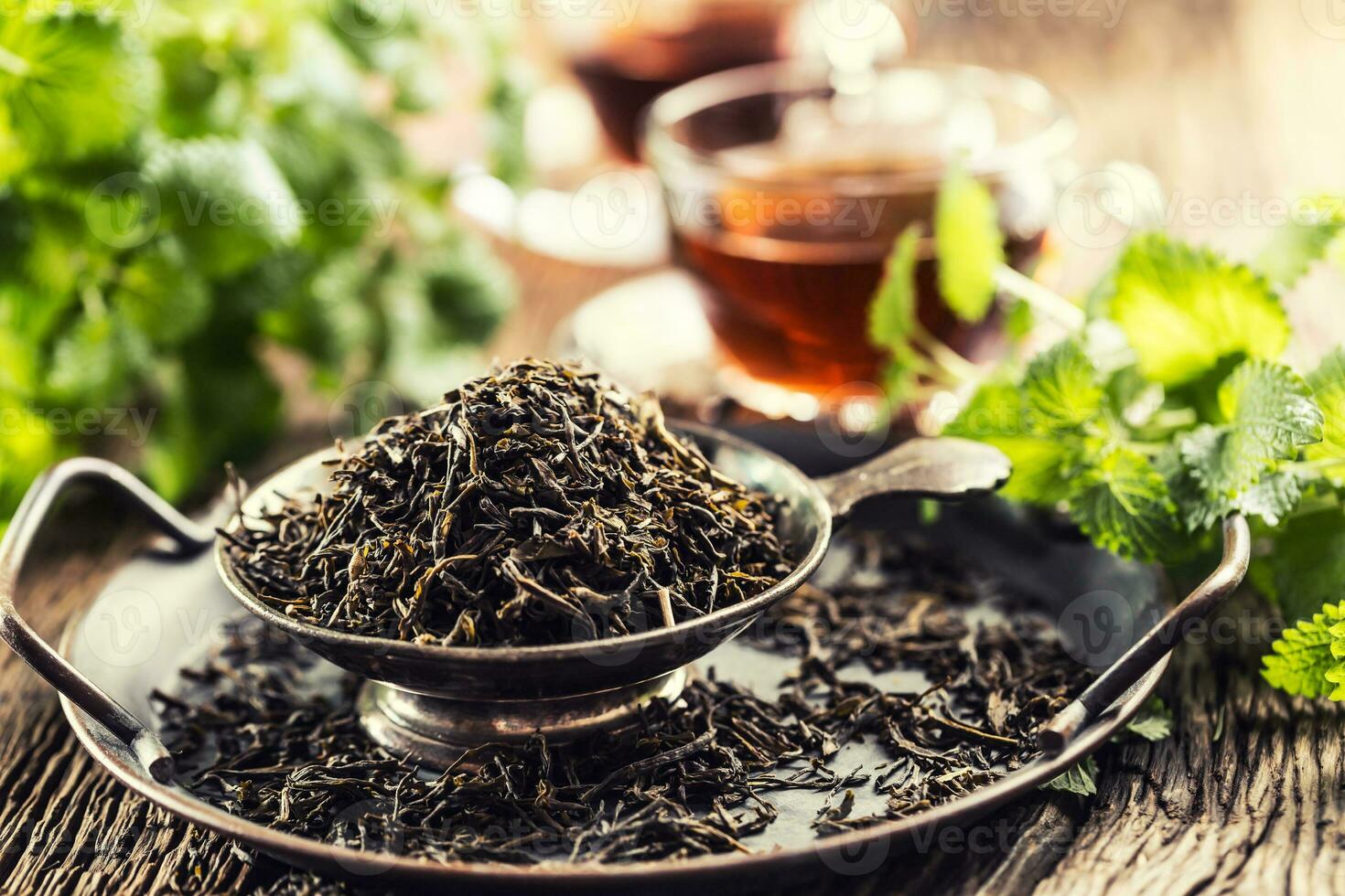 Dried tea leaves in bowl on rustic wooden table photo