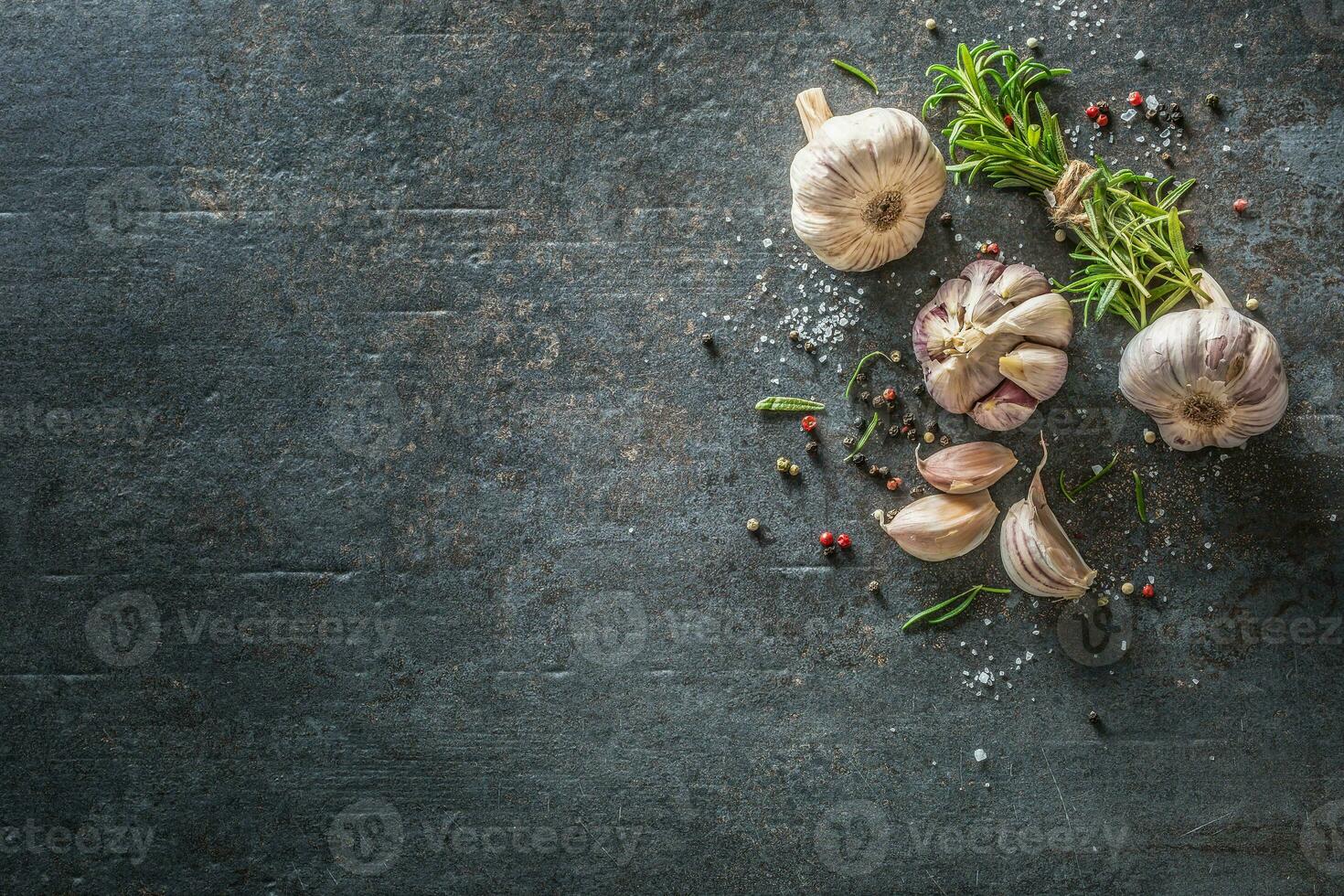 Garlic cloves and bulb with fresh rosemary salt and spice on concrete table photo