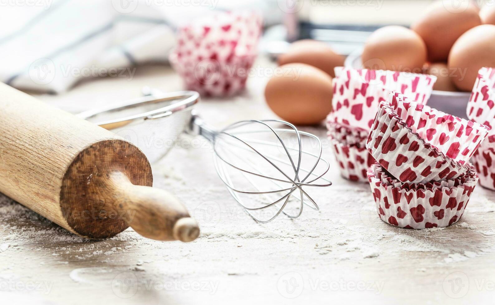 Baking utensils with eggs flour and cupcake cases on kitchen table - Close up photo