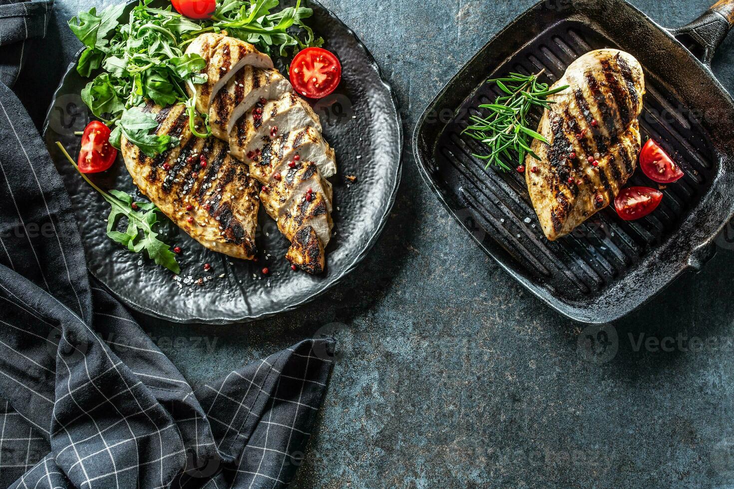 Chicken breast grilled with spices peper salt tomatoes rosemary and arugula - Top of view photo