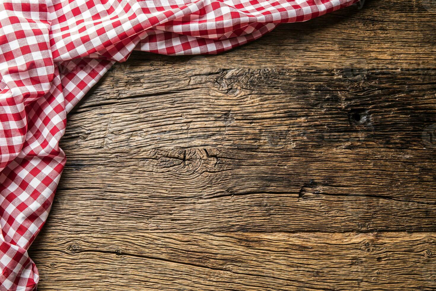 Red checkered kitchen tablecloth on rustic wooden table photo