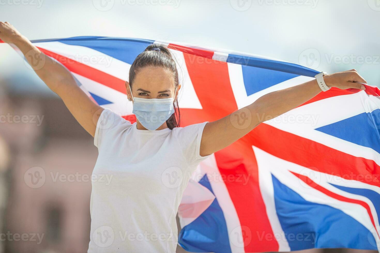 Young woman in a protective mask holds UK flag during pandemic photo