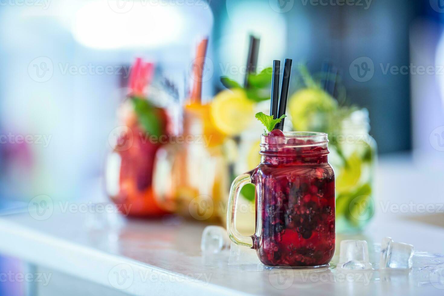 Various lemonades in mason jars with orange lime lemon otange strawberries and fresh fruit fruits photo