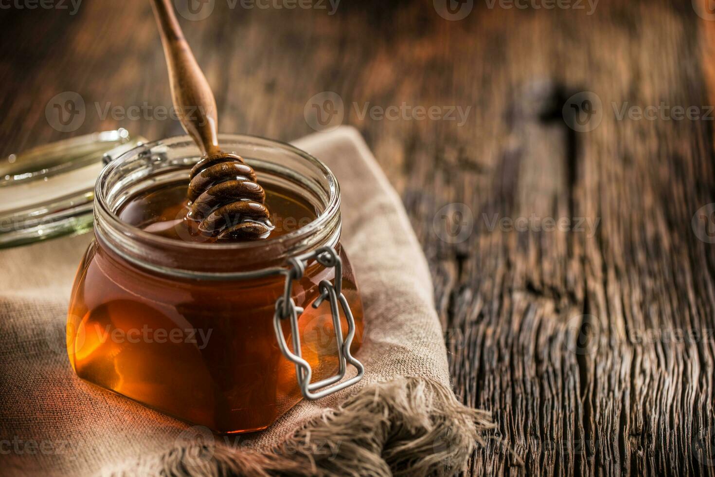 Honey jar with dipper on old woodn table photo