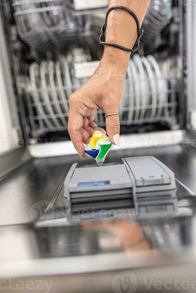 Dissolving dishwasher tablet put into the device  before starting the dishes cleaning cycle photo