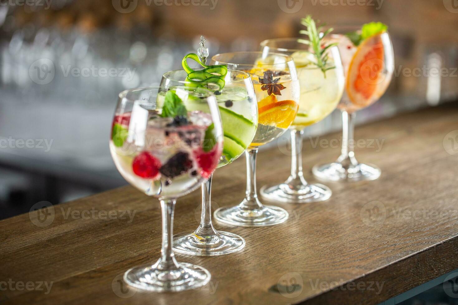 Gin tonic long drink as a classic cocktail in various forms with garnish in individual glasses such as orange, lemon, grapefruit, cucumber or berries photo