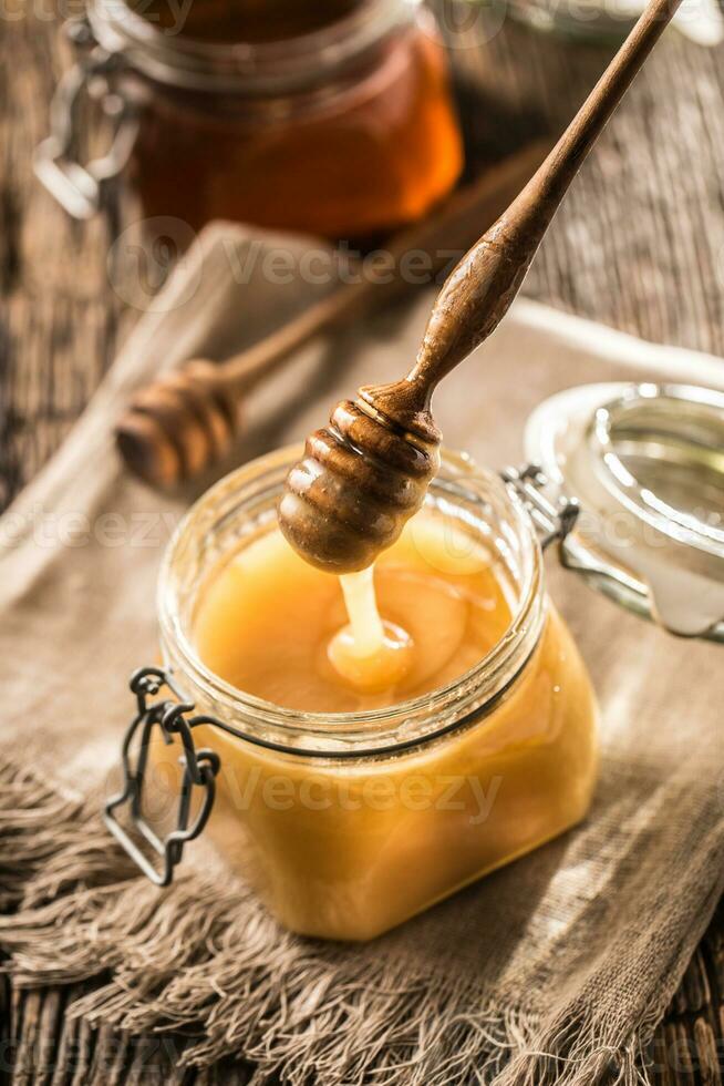 miel en frascos y cazo en rústico roble mesa foto