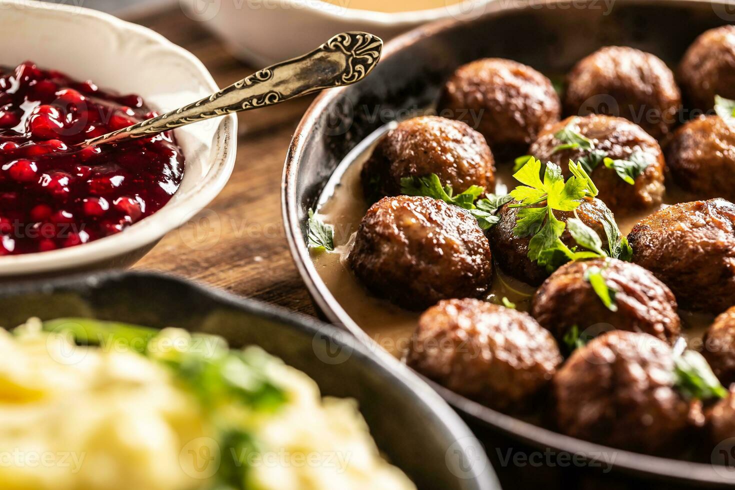 Swedish food Kottbullar meatballs, served in a pan with mashed potatoes, parsley and cranberry sauce photo