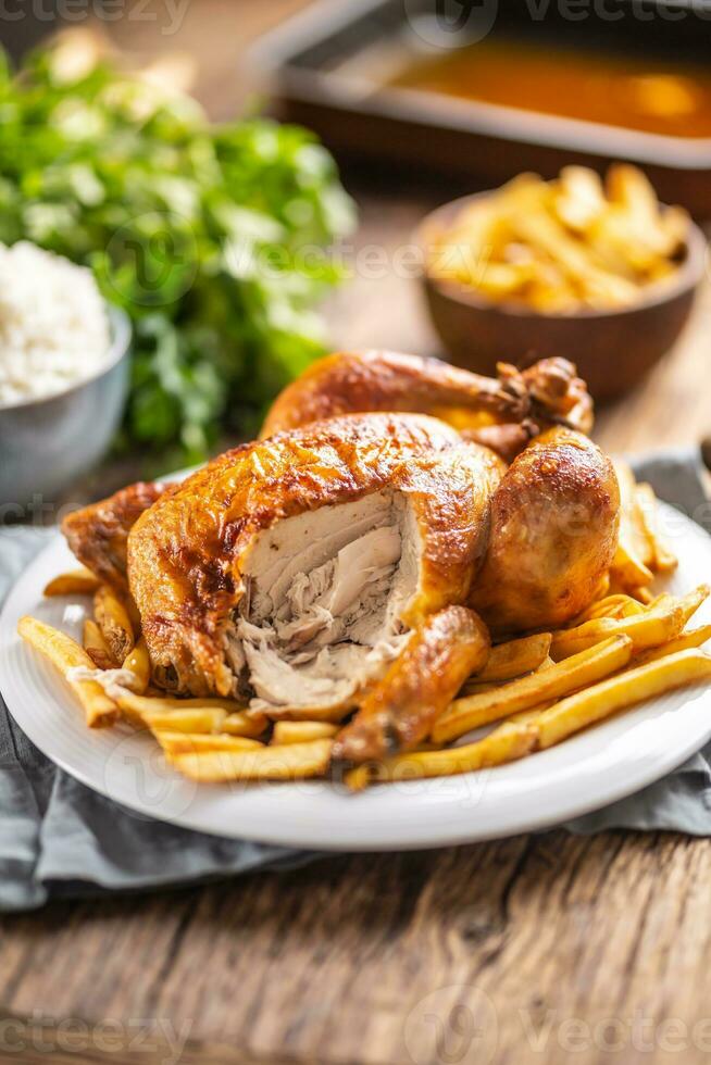Very tasty roasted chicken whole on a plate and wooden table photo