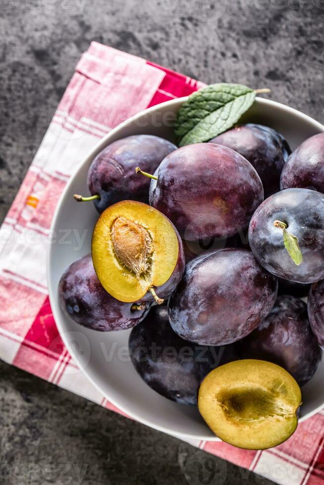 Plums. Fresh juicy plums in a bowl on a wooden or concrete board photo