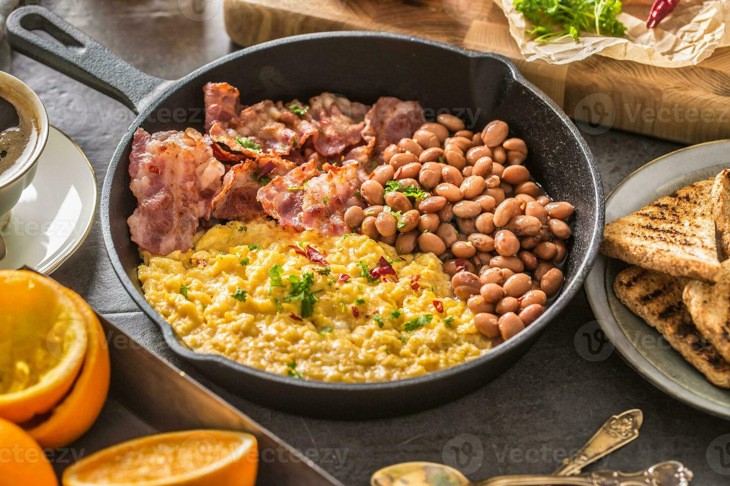 Full table of english breakfast. Scrambled eggs grilled bacon beans toast bread orange juice and coffee photo
