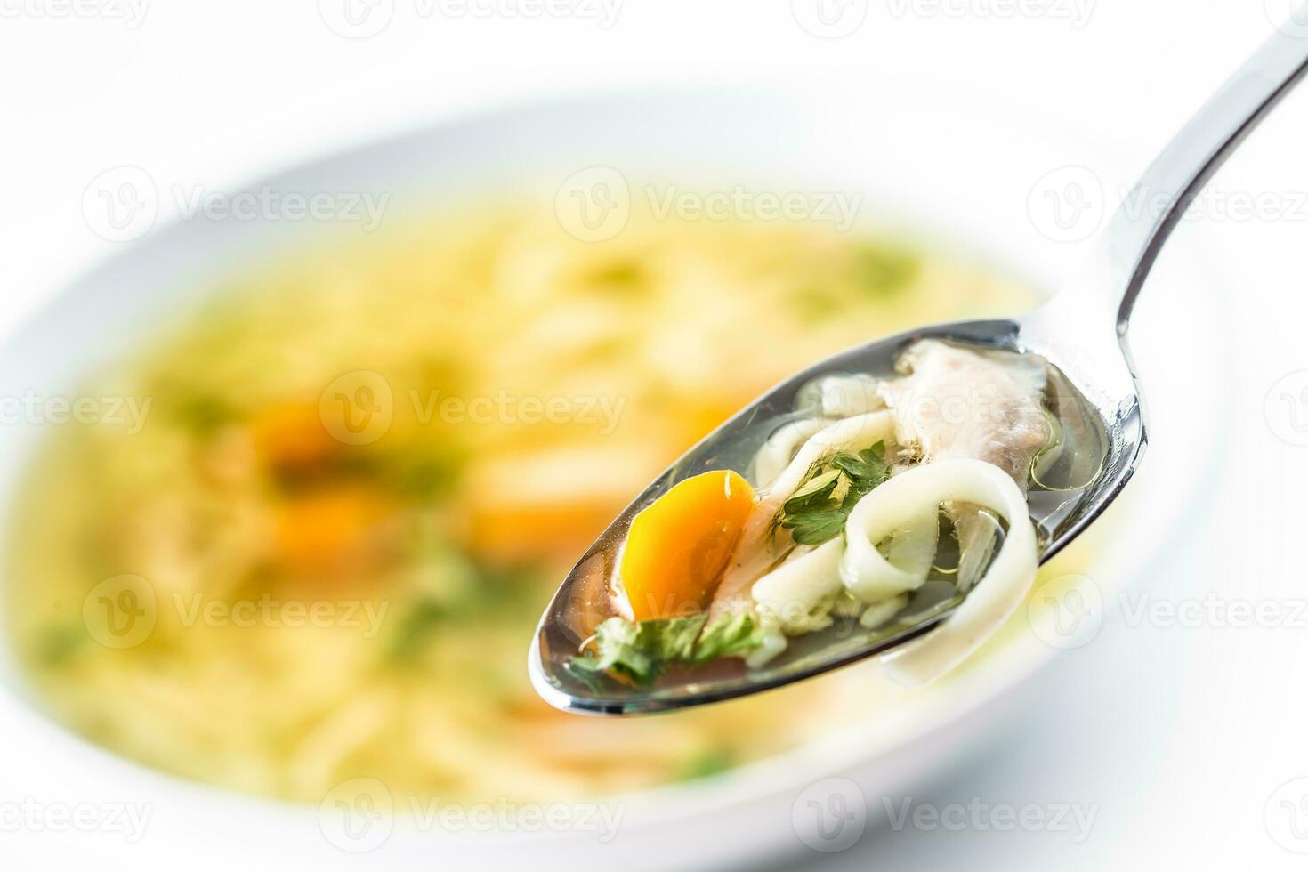 Spoon full of chicken or beef soup with noodles carrot and herbs photo
