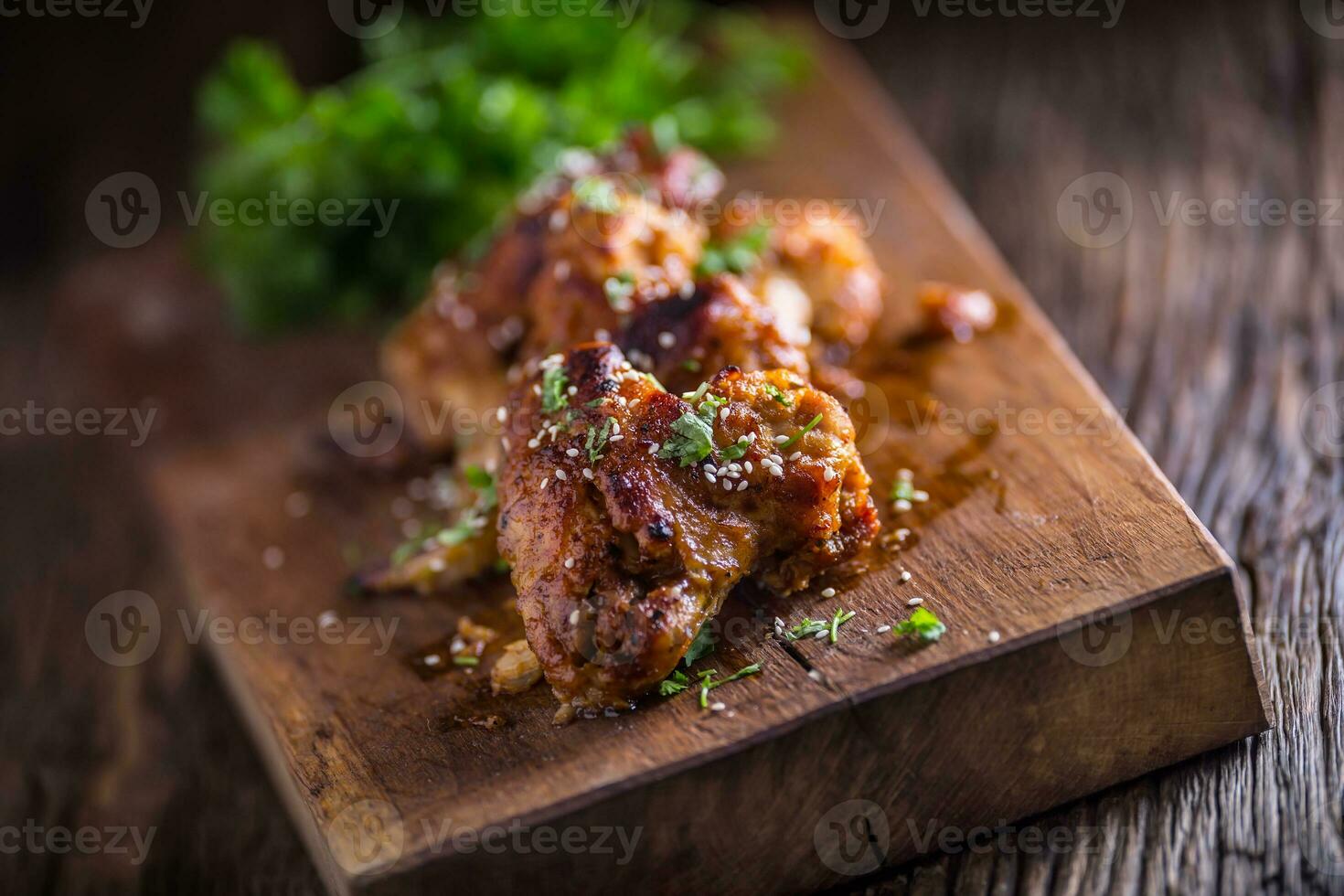 Chicken wings grilled BBQ  parsley herb and sesame on wooden board. photo