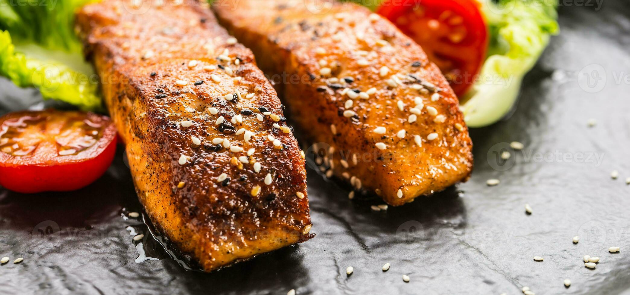 delicioso A la parrilla asado salmón filetes o filetes con sésamo Tomates y lechuga ensalada. foto