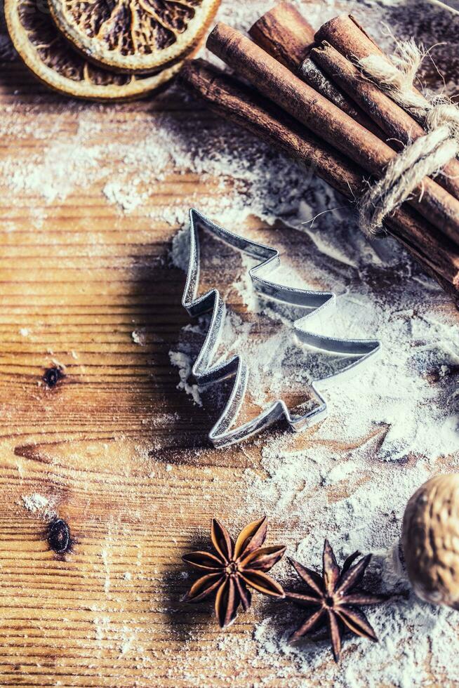 Top of view bakery table full of christmas aromatic ingredients star anise cinnamon dried orange flour cookery book and cookie cutters photo