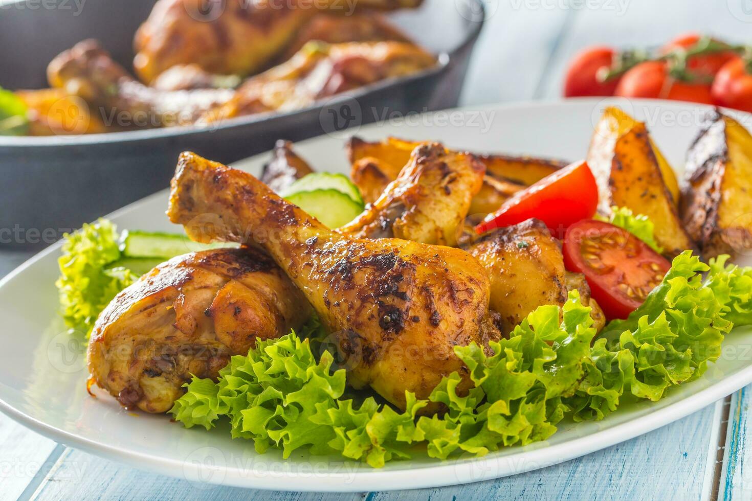 Roasted chicken legs with lettuce salad and tomatoes photo