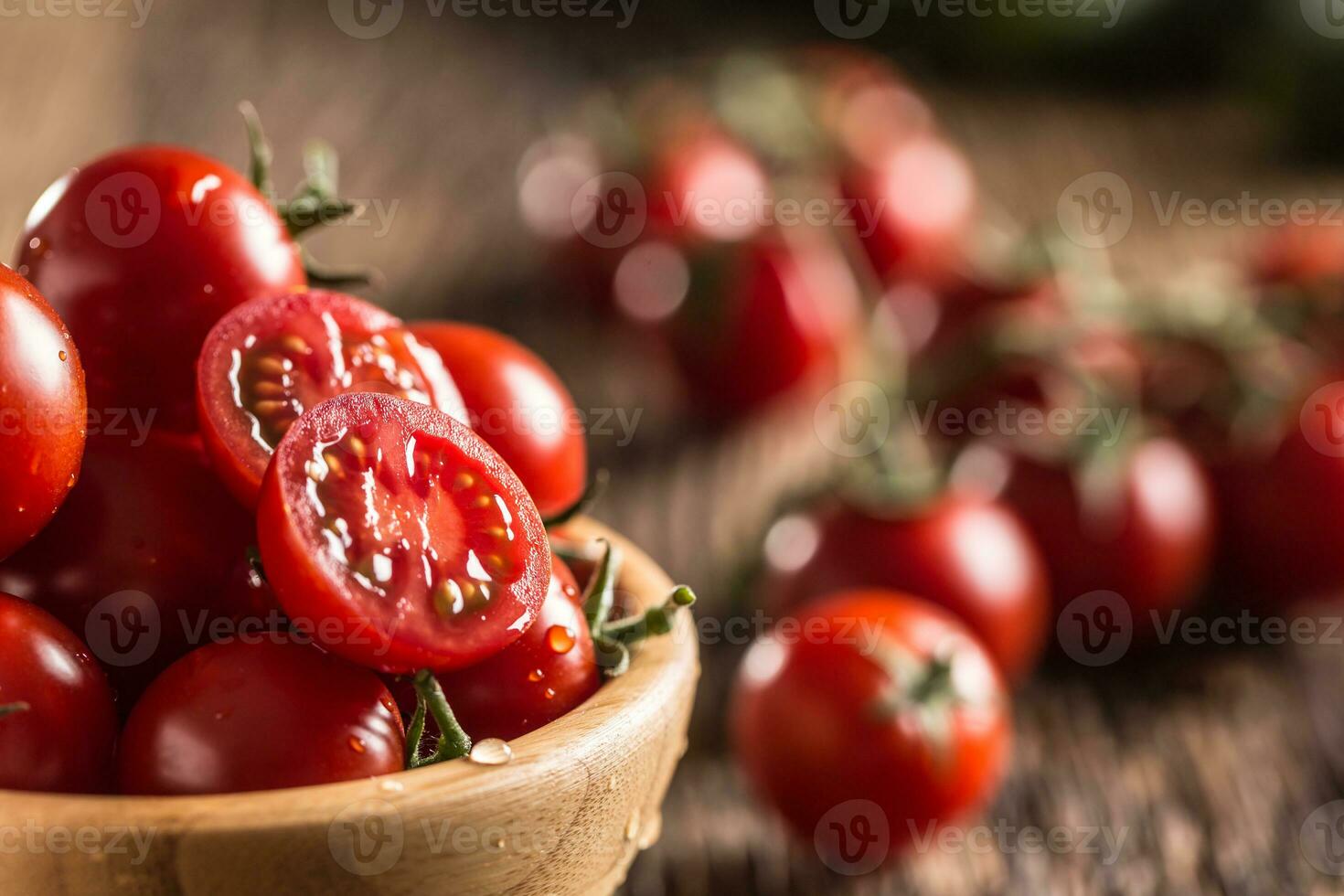 Fresh cherry tomatoes in wooden bowl on old oak table photo