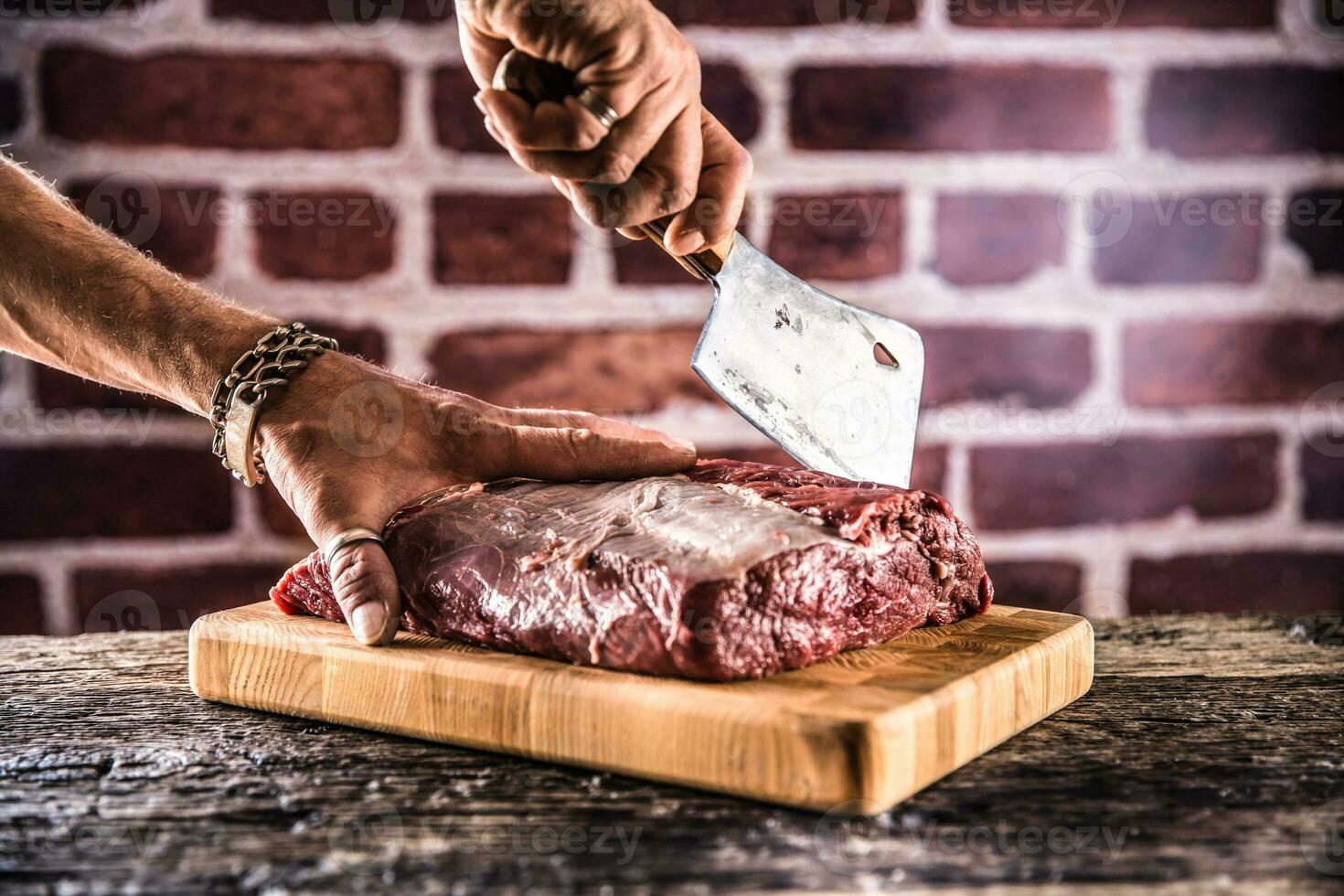 Butcher man hands cutting raw beef steak in butchery photo