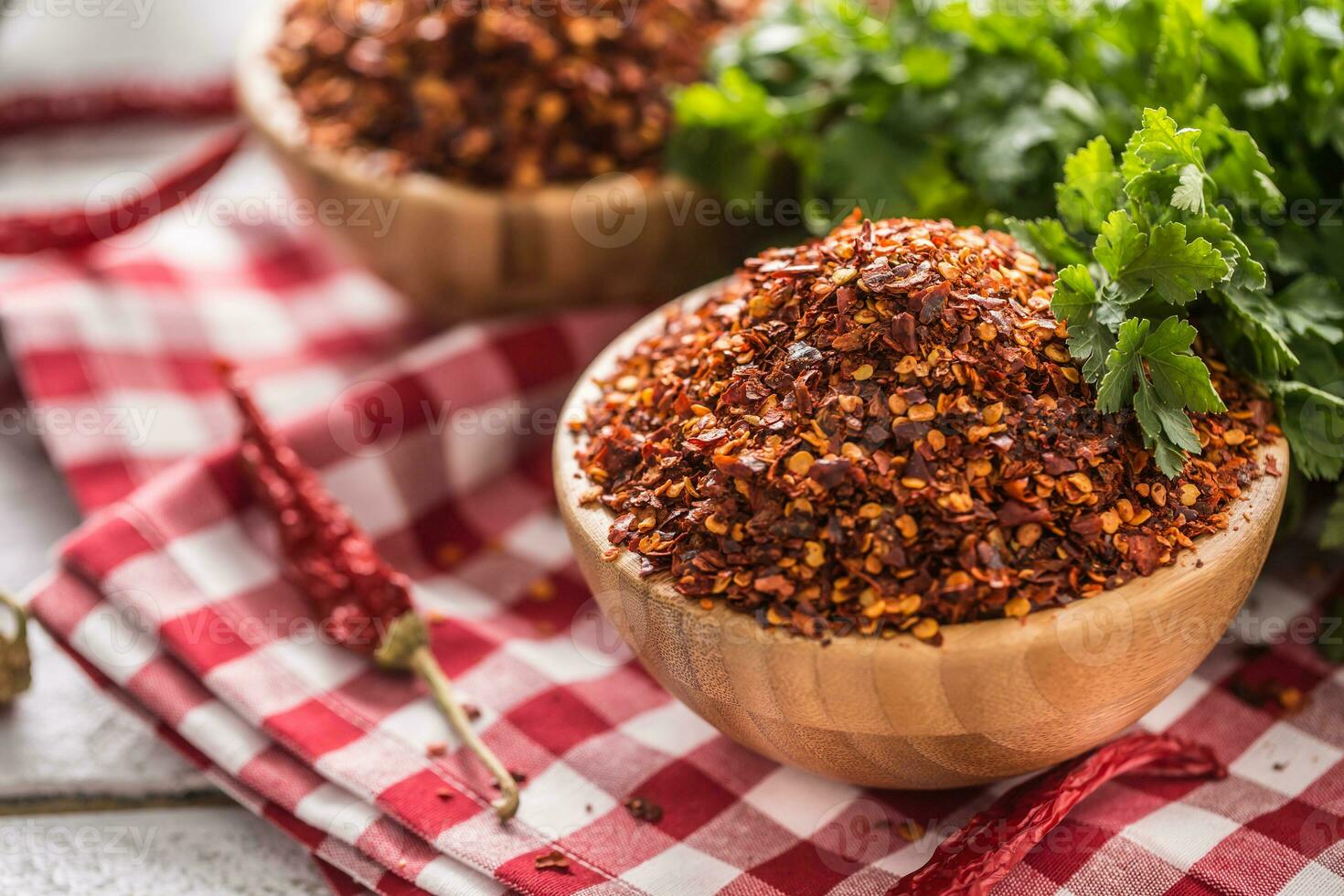 Dried and crushed chili peppers in wooden bowles with parsley herbs photo