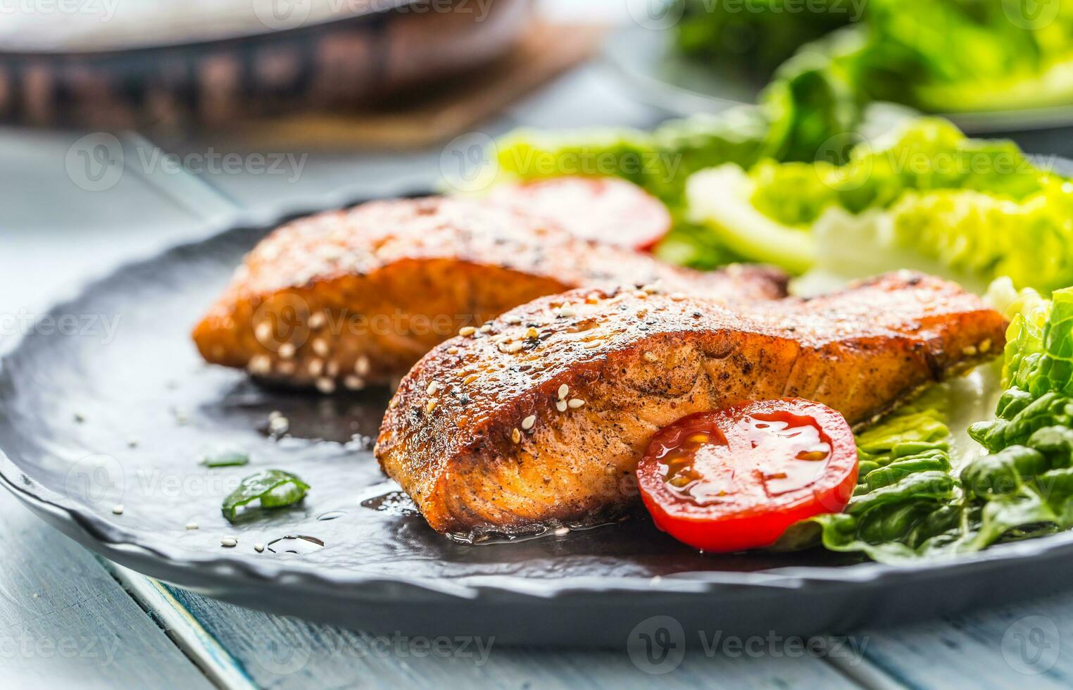 delicioso A la parrilla asado salmón filetes o filetes con sésamo Tomates y lechuga ensalada. foto