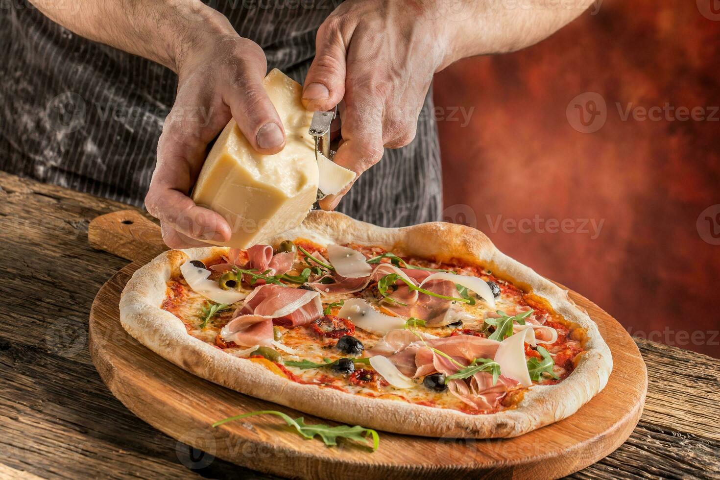 Pizza and Chef. Chef in the restaurant prepares a pizza and decorates it with parmesan cheese photo