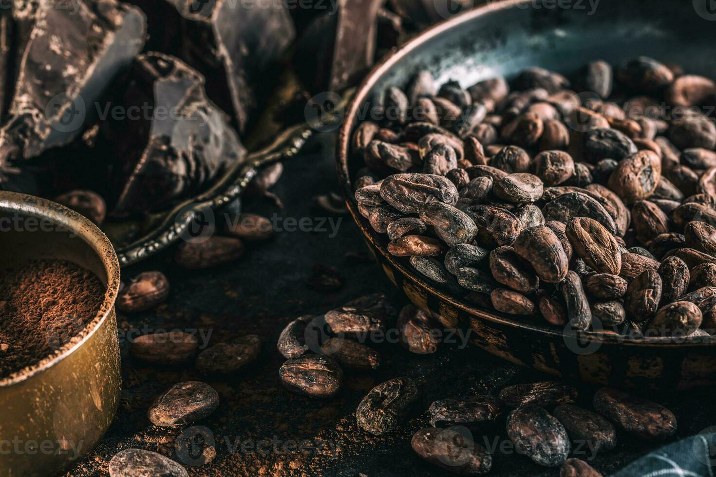 Dark chokolate cocoa beans and powder on concrete table photo