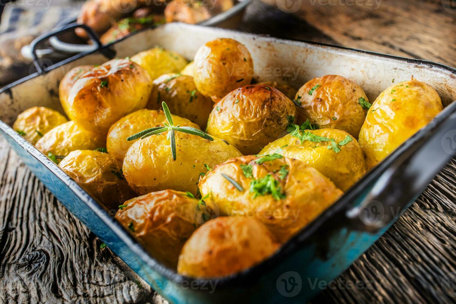 Roasted potatoes with herbs in pan on rustic oak table photo
