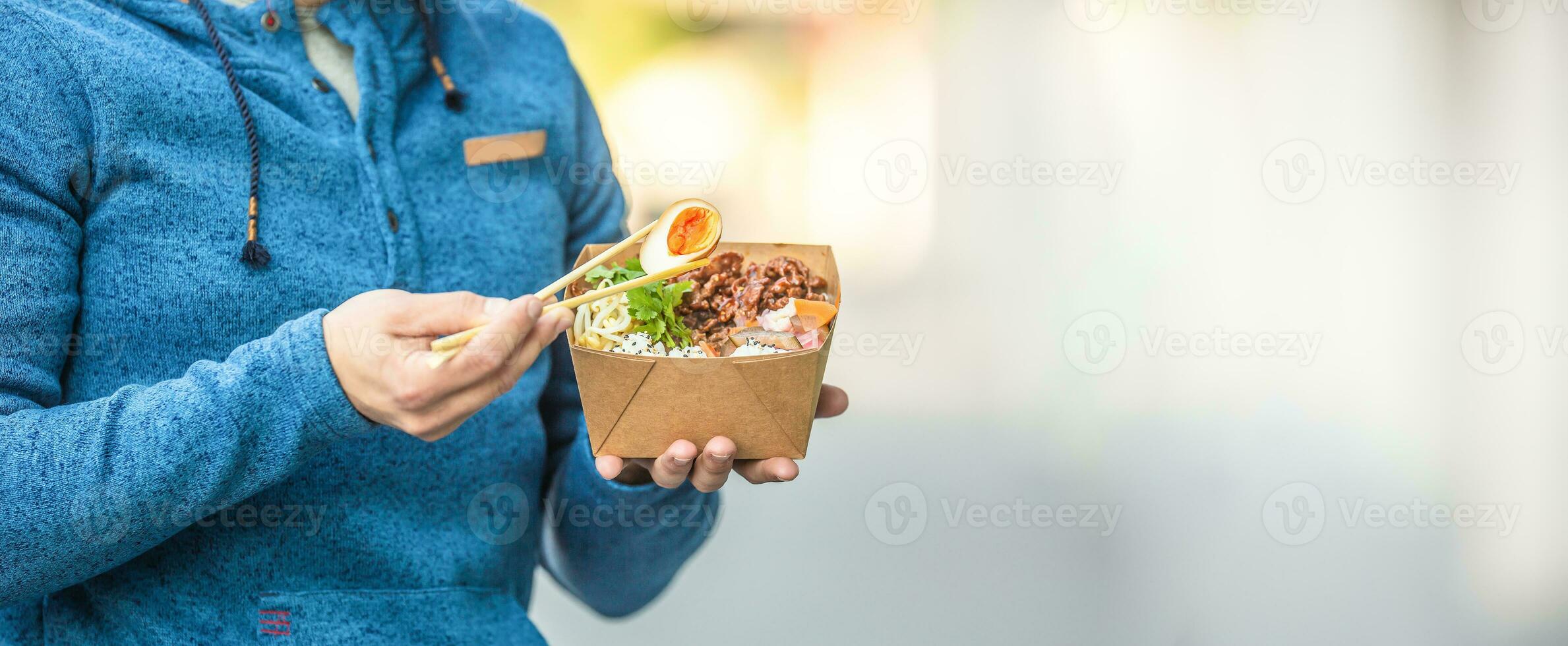 Young man's hands holding lunch in a box of recycled paper photo