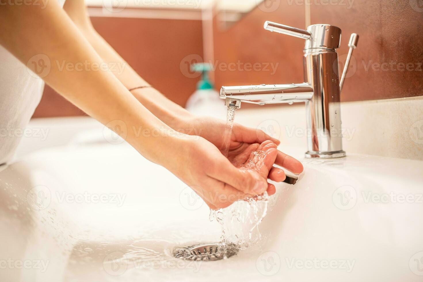 Lavado manos con agua y líquido jabón en el baño foto