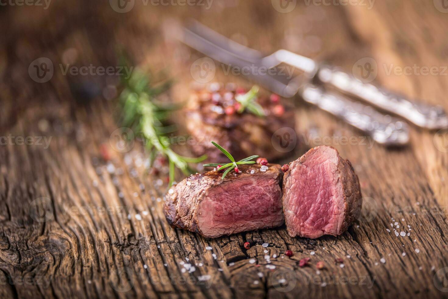 Grilled beef steak with rosemary, salt and pepper on old cutting board. Beef tenderloin steak. photo