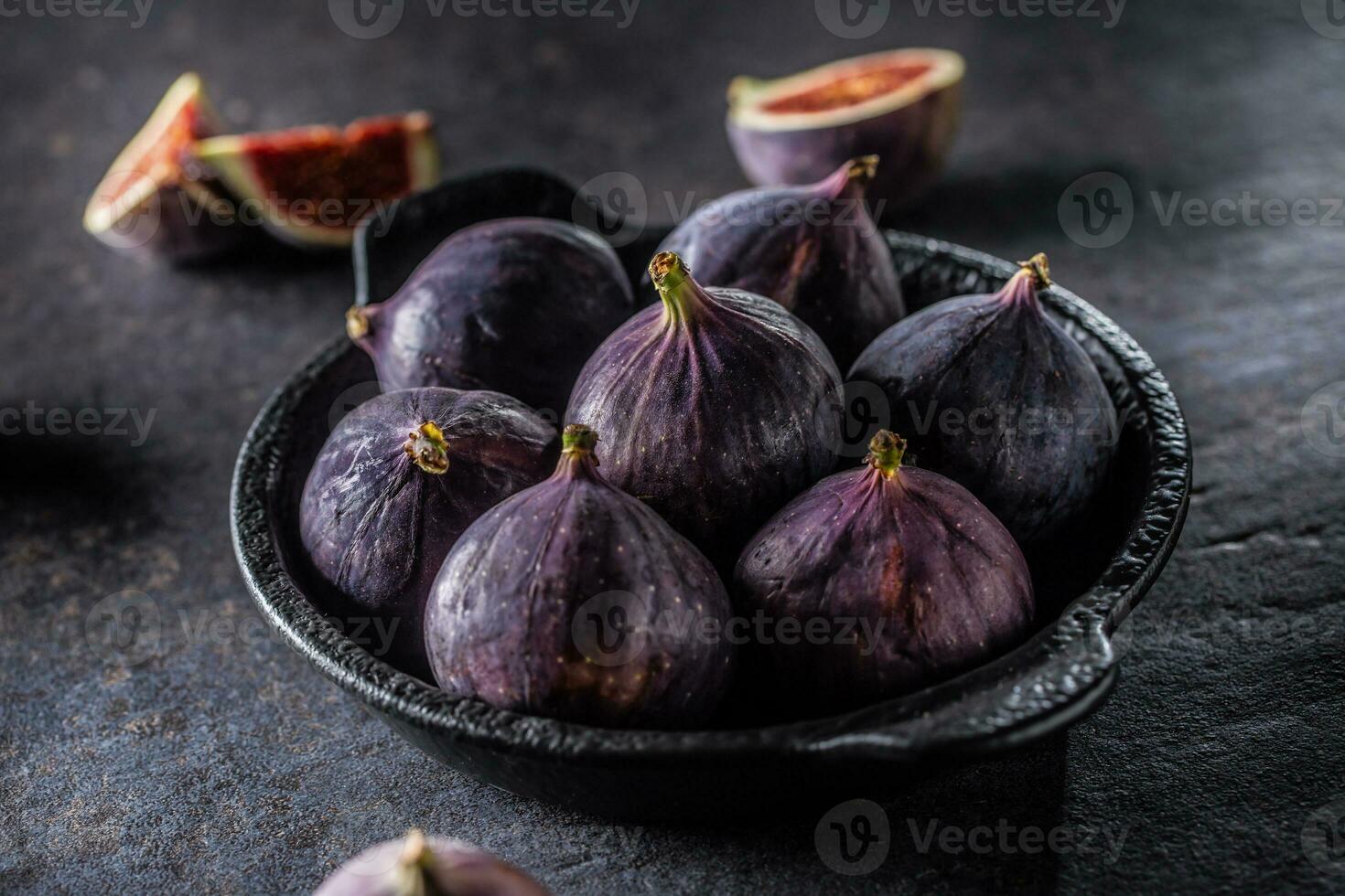 A few figs in a black bowl on an dark concrete table photo