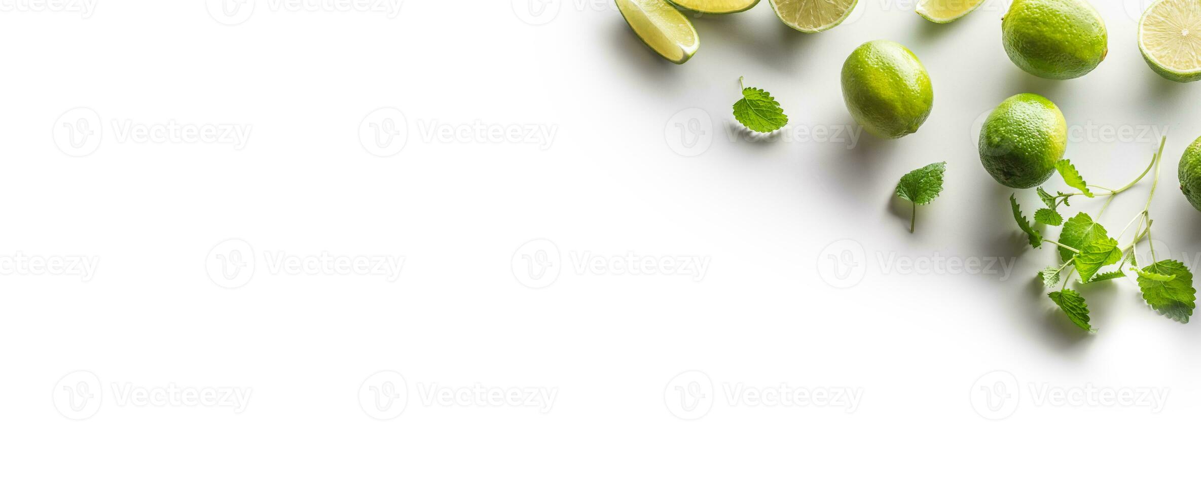 Sliced and whole limes with mint leaves on an isolated white banner background photo