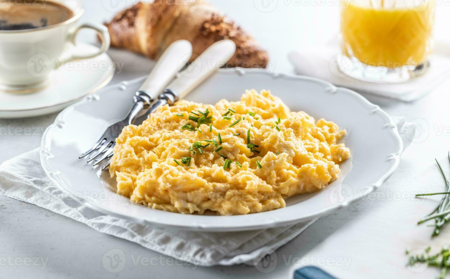 Hotel restaurant serving scrambled eggs with chives next to pastry and beverages photo