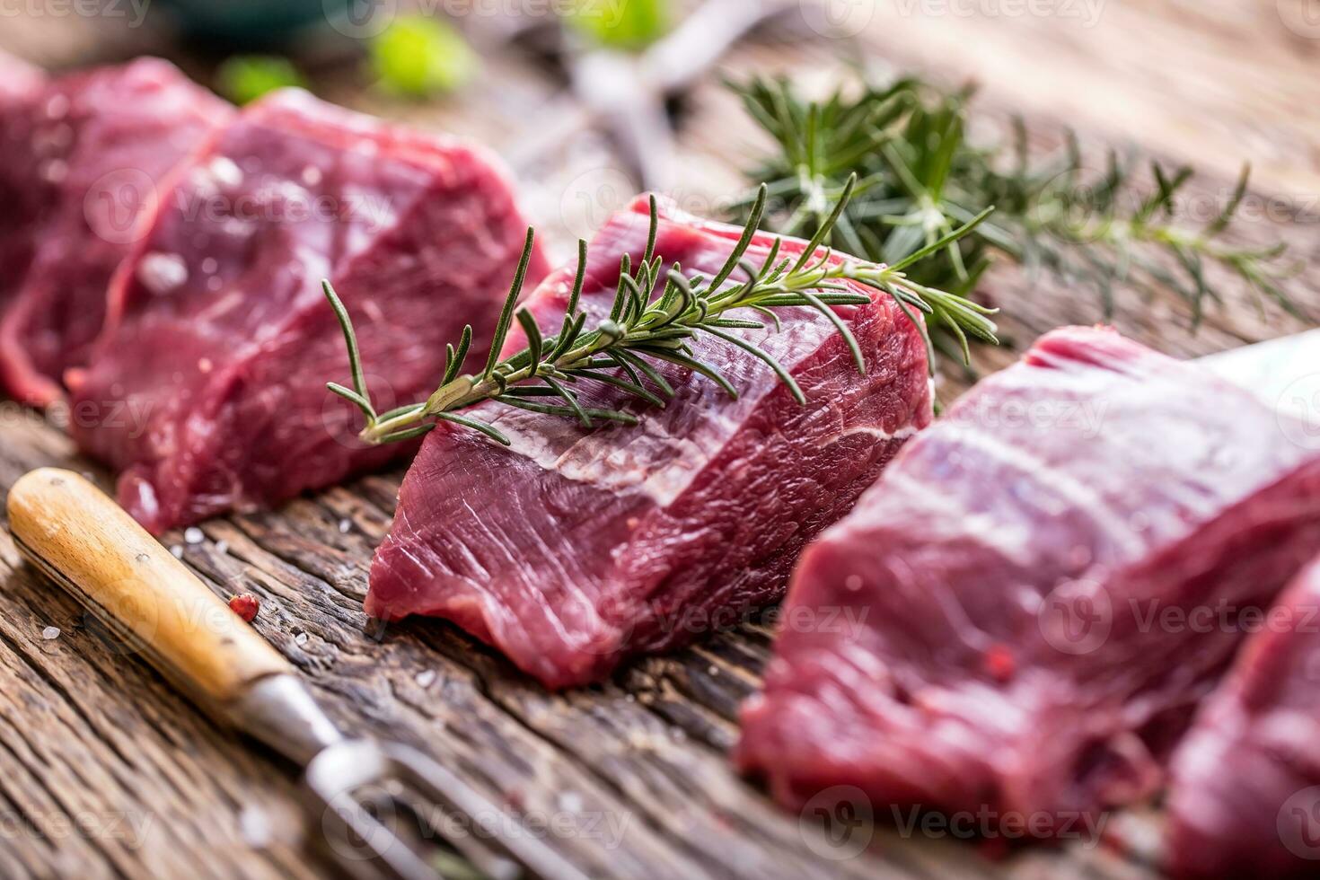 Raw beef meat. Raw beef tenderloin steak on a cutting board with rosemary pepper salt in other positions. photo