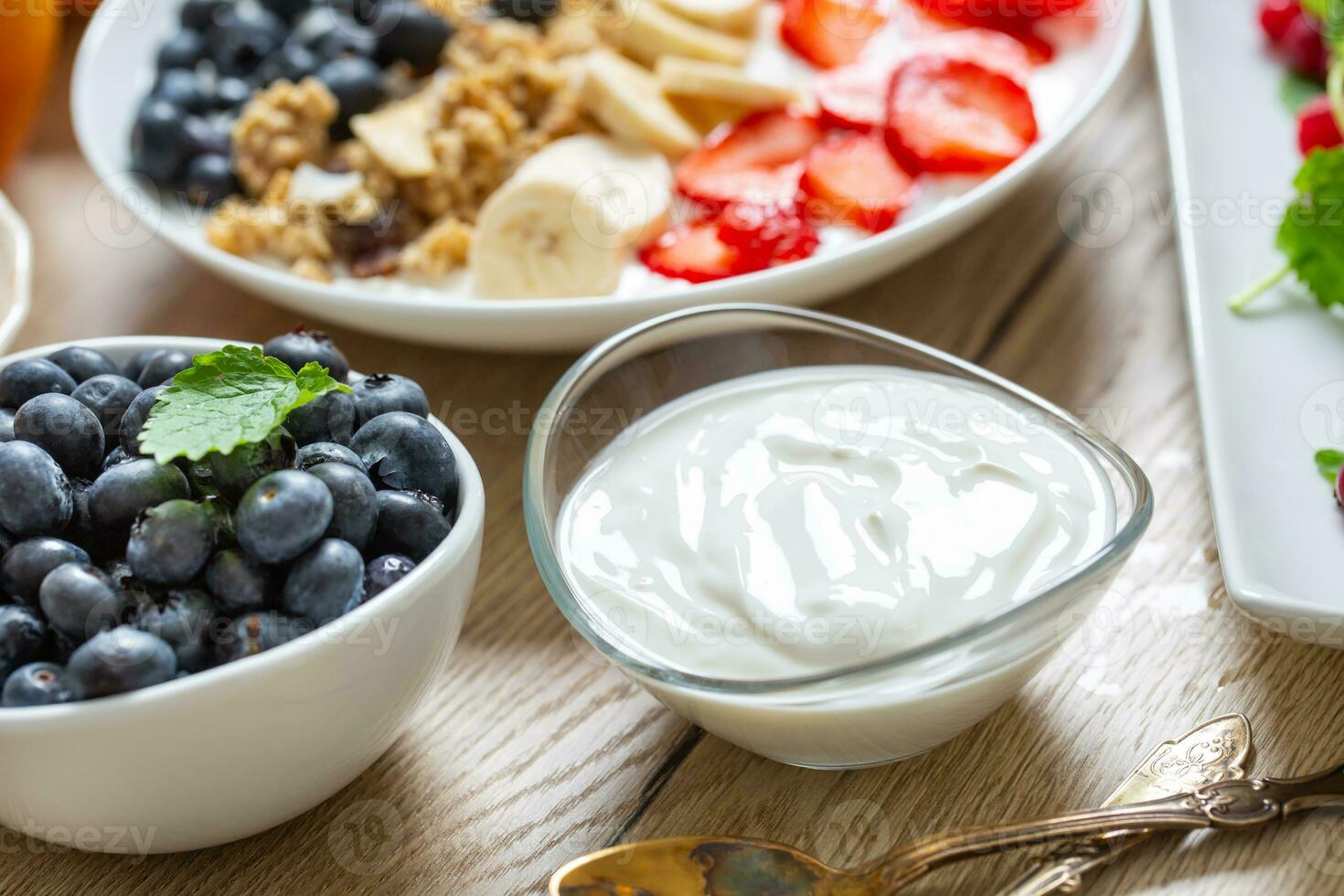 Yogurt in a glass  bowl with healthy breakfast on table photo