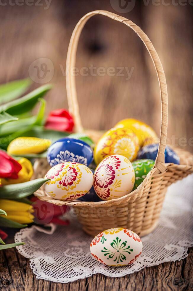 Pascua de Resurrección. mano hecho pintado Pascua de Resurrección huevos en cesta y primavera tulipanes foto