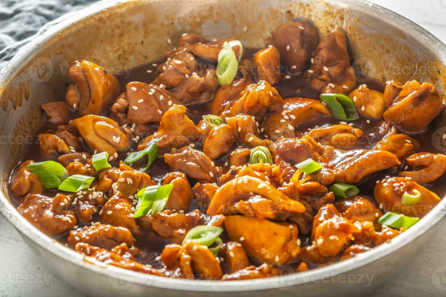 Freshly cooked chicken stew in a metal bowl with spring onion and seesame sprinkle photo